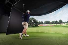 Player mid-swing in a professional indoor golf simulator facing a panoramic course display
